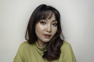 un visage joyeux de beauté de jeune mannequin asiatique portant un haut vert. soin du visage beauté soins de la peau, spa, concept de santé féminine. photo