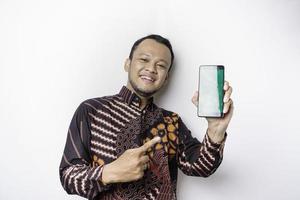 portrait d'un homme asiatique souriant portant une chemise batik et montrant un écran vert sur son téléphone, isolé sur fond blanc photo