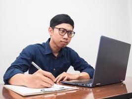 jeune homme d'affaires écrivant un stylo sérieux avec un espace de travail de table photo