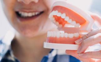 concept de stomatologie, portrait partiel d'une fille avec de fortes dents blanches regardant la caméra et souriant, les doigts près du visage. gros plan sur une jeune femme chez le dentiste, en studio, à l'intérieur photo