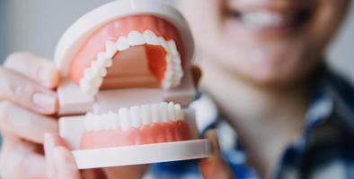 concept de stomatologie, portrait partiel d'une fille avec de fortes dents blanches regardant la caméra et souriant, les doigts près du visage. gros plan sur une jeune femme chez le dentiste, en studio, à l'intérieur photo