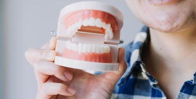 concept de stomatologie, portrait partiel d'une fille avec de fortes dents blanches regardant la caméra et souriant, les doigts près du visage. gros plan sur une jeune femme chez le dentiste, en studio, à l'intérieur photo