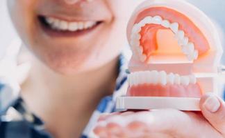 concept de stomatologie, portrait partiel d'une fille avec de fortes dents blanches regardant la caméra et souriant, les doigts près du visage. gros plan sur une jeune femme chez le dentiste, en studio, à l'intérieur photo