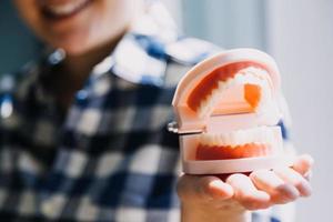 concept de stomatologie, portrait partiel d'une fille avec de fortes dents blanches regardant la caméra et souriant, les doigts près du visage. gros plan sur une jeune femme chez le dentiste, en studio, à l'intérieur photo