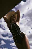 portrait d'une femme en maillot de bain, chapeau et lunettes de soleil en été sur la berge contre le ciel photo