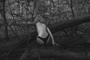 femme nue assise sur un arbre tombé photographie panoramique monochrome photo