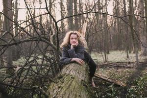 femme blonde assise sur un grand arbre tombé photographie panoramique photo