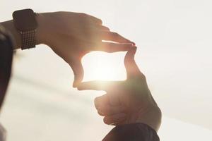 concept de planification et de vision du début de la nouvelle année, des mains de femme faisant un geste de cadre trouvent la mise au point au coucher du soleil, une femme à la recherche de perspective pour saisir le sens d'une cible claire à venir. photo