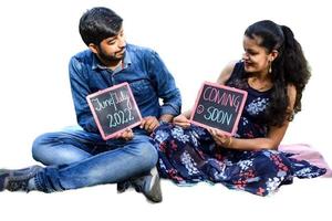 couple indien posant pour le tournage de bébé de maternité avec un fond uni blanc. le couple pose dans une pelouse avec de l'herbe verte et la femme étale sa bosse de bébé dans le jardin de lodhi à new delhi, inde photo