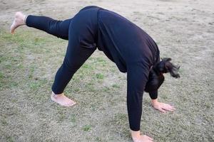 jeune femme indienne pratiquant le yoga en plein air dans un parc. belle fille pratique la pose de yoga de base. calme et détente, bonheur féminin. poses de yoga de base en plein air photo