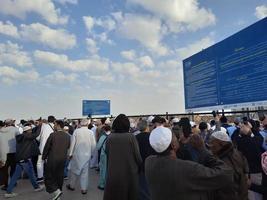 médina, arabie saoudite, décembre 2022 - vue nocturne du cimetière historique jannat al-baqi de médina. des pèlerins de différents pays du monde se trouvent près du panneau d'orientation du cimetière de jannat al baqi. photo