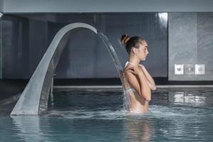 jeune femme touchant les épaules pendant l'hydrothérapie photo