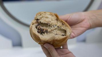 Main de femme tenant un beignet au chocolat sur un fond blanc. photo