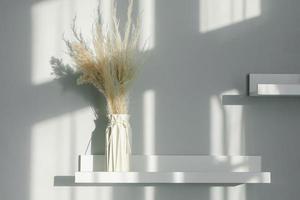 décor floral intérieur de la maison. fleurs séchées dans un vase sur une étagère blanche. fond avec des lumières d'ombre photo