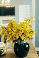 bouquet de fleurs de mimosa jaune dans un vase en verre sur une table en bois. 8 mars, concept de la journée de la femme photo