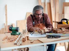 un homme senior asiatique heureux profite de son passe-temps en peignant avec diligence des nichoirs dans l'atelier. photo