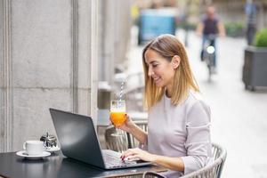 Happy female pigiste travaillant sur netbook dans une cafétéria en plein air