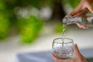 verser de l'eau d'une bouteille dans un verre. verser un verre d'eau. une image de verser un verre d'eau photo