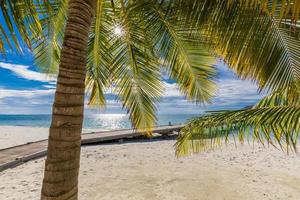 paysage exotique des maldives. plage de l'île tropicale avec rayons de soleil. concept de ciel de sable de mer idyllique et paisible. fond de plage tropicale comme paysage d'été, vacances de scène et vacances photo