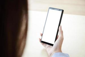 une femme tenant un smartphone noir avec un écran blanc se connecte aux communications technologiques en ligne. concept de smartphone avec écran, espace libre pour copier du texte ou du contenu informatif. chemin de détourage photo