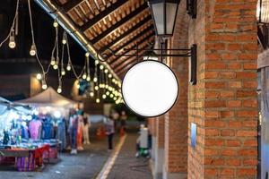 la boîte à lumière blanche circulaire a été accrochée au mur devant le poteau de brique dans un centre commercial communautaire vintage à environnement ambiant de tungstène. photo