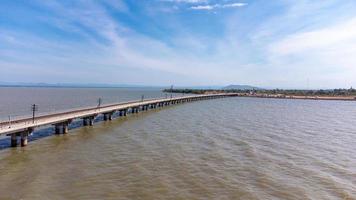 vue aérienne d'un incroyable train de voyage garé sur un pont ferroviaire flottant au-dessus de l'eau du lac dans le barrage de pa sak jolasid avec un ciel bleu à lopburi, en thaïlande. photo