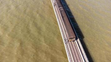 vue aérienne d'un incroyable train de voyage garé sur un pont ferroviaire flottant au-dessus de l'eau du lac dans le barrage de pa sak jolasid avec un ciel bleu à lopburi, en thaïlande. photo