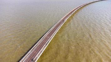 vue aérienne d'un incroyable train de voyage garé sur un pont ferroviaire flottant au-dessus de l'eau du lac dans le barrage de pa sak jolasid avec un ciel bleu à lopburi, en thaïlande. photo