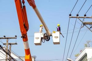 électriciens travaillant sur le téléphérique pour réparer la ligne électrique sous fond de ciel bleu clair. photo