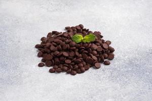 gouttes de chocolat sur un fond de béton gris. morceaux de chocolat pour la décoration des desserts. photo