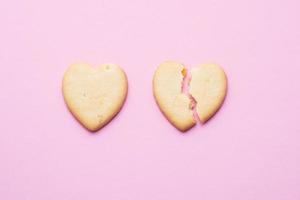 biscuits en forme de coeur, un coeur fissuré sur fond rose, le concept d'une relation brisée.