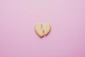 biscuits en forme de coeur, un coeur fissuré sur fond rose, le concept d'une relation brisée.