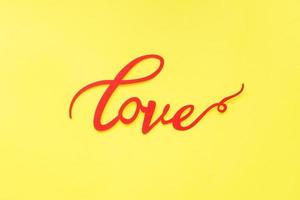 le mot amour et coeurs rouges sur fond jaune, vue de dessus. carte de vacances pour la saint valentin. mise à plat. photo