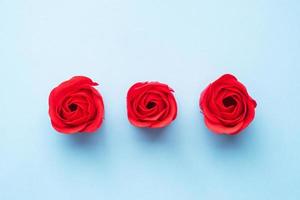 savon artisanal en forme de rose, fleur rose rouge sur fond bleu. vue de dessus, minimaliste, espace de copie. photo