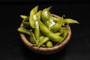 salade de haricots edamame au sel de mer servie dans un bol sombre. isolé sur fond noir. nourriture de restaurant. cuisine japonaise photo