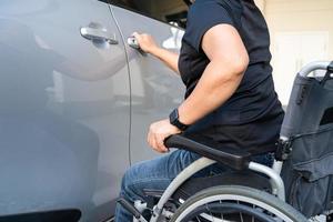 femme asiatique pliant et soulevant le fauteuil roulant dans sa voiture. notion d'accessibilité. photo