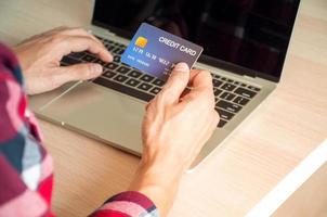 concept de paiement en ligne, les mains de jeunes hommes utilisant des cartes de crédit et utilisant des ordinateurs pour faire des achats en ligne ou payer des factures en ligne.