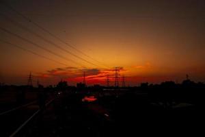 silhouette de pylônes électriques à haute tension avec des paysages colorés après le coucher du soleil photo