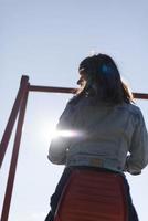 une femme infantile et heureuse assise sur un toboggan pour enfants sur une aire de jeux photo