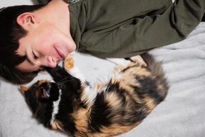 garçon adolescent avec minou allongé sur le canapé. l'amour des enfants pour les animaux. photo