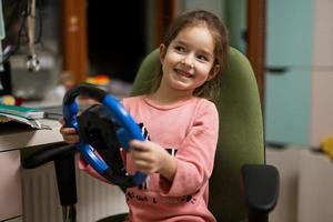 fille assise sur une chaise avec le volant d'un enfant dans ses mains dans la chambre des enfants. photo