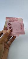 portrait de billets indonésiens rp. 100 000 en main. Monnaie roupie indonésienne isolé sur fond blanc photo