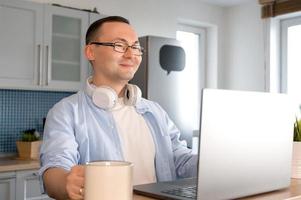 un homme asiatique souriant à lunettes utilise un ordinateur portable pour faire du shopping, programmer, travailler, etc. photo