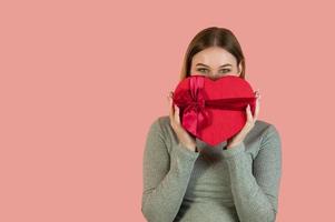 portrait en studio d'une femme souriante tenant une boîte-cadeau en forme de coeur.bannière avec place pour le texte photo