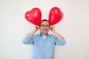 portrait d'un homme drôle et heureux avec deux ballons en forme de coeur. concept de la saint valentin photo