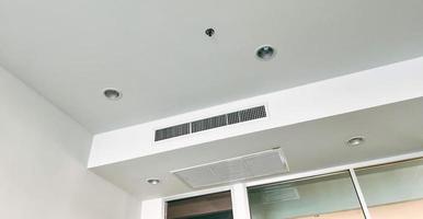 climatiseur de type cassette monté au plafond et lampe moderne au plafond blanc. climatiseur gainable pour la maison, le hall ou le bureau. photo