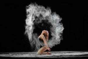 belle jeune femme avec de la farine étalée sur l'air sur un fond noir photo