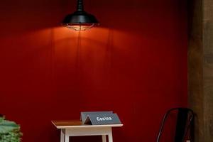 table en bois avec une seule chaise, sur fond rouge, lampe lumineuse de qualité, mexique photo