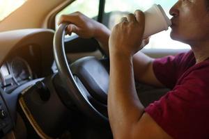 gros plan homme boit du café à partir d'une tasse de papier dans la voiture. concept, baverge pour se rafraîchir ou aider à se réveiller pendant la conduite qui peut provoquer un accident de voiture. photo