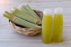 bouteilles de jus de canne à sucre frais. et bagasse après avoir pressé pour boire un verre dans un panier. concept, boisson naturelle saine à base de cultures agricoles. boissons maison, a des propriétés médicinales et à base de plantes photo